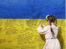 дівчинка пише на прапорі України