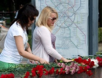 Люди приносят цветы ко входу станции метро