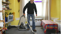 Мужчина пылесосит комнату
