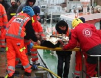 Спасатели выносят на берег потерпевших кораблекрушение