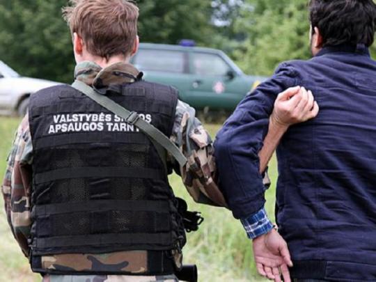Литовский пограничник ведет задержанного нелегала