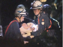 Спасатели держат младенца