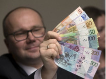 Представитель банка держит новые белорусские банкноты
