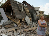 Женщина возле разрушенного дома на Донбассе