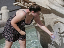 Женщина набирает воду в фонтане