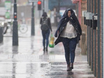 Женщина закрывается курткой от дождя