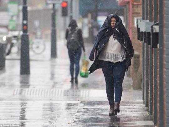 Женщина закрывается курткой от дождя