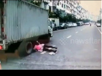 Кадр из видео: женщина лежит под грузовиком