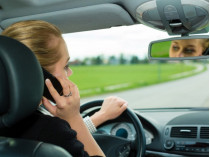Женщина говорит по телефону за рулем