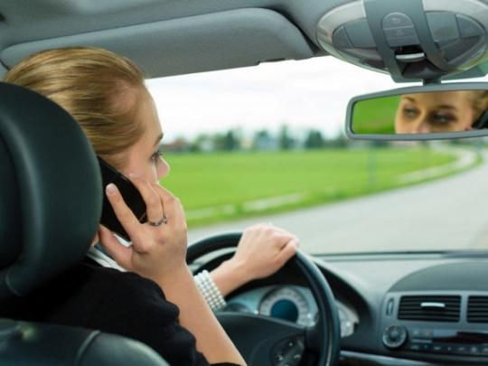 Женщина говорит по телефону за рулем