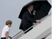 Трамп поднимается по трапу с зонтом, сзади&nbsp;— его сын