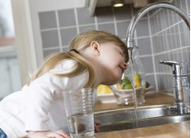 Девочка пьет воду из-под крана