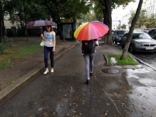 люди прячутся под зонтиками от дождя
