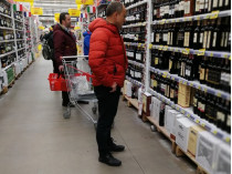Человек в супермаркете выбирает алкоголь