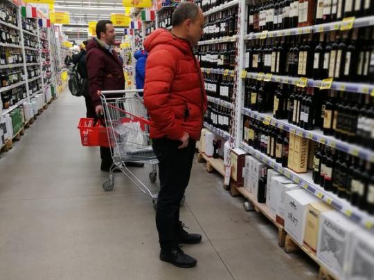 Человек в супермаркете выбирает алкоголь