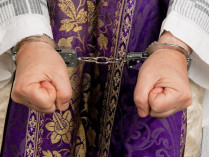 Руки католического священника в наручниках