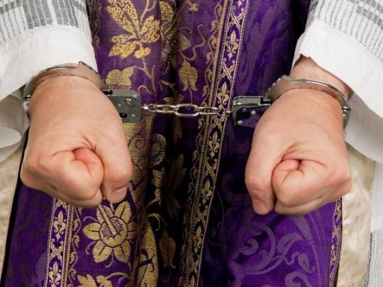 Руки католического священника в наручниках