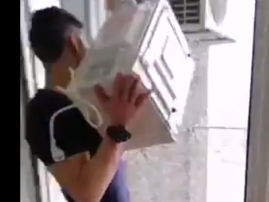 парень выбрасывает с балкона микроволновку