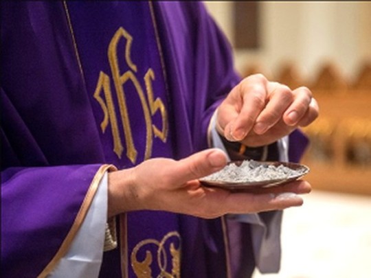 Католический священник в фиолетовом облачении с пеплом для посыпания голов верующих