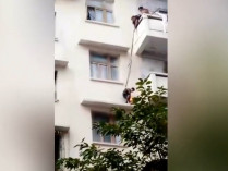Мальчик спускается с балкона за кошкой