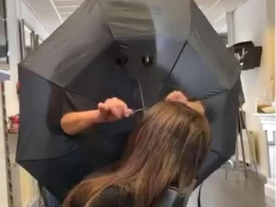 Парикмахер стрижет клиентку через зонтик