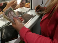 Женщина получает в кассе деньги