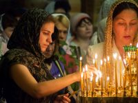 Женщины в церкви зажигают свечи 