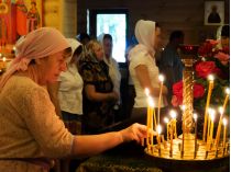 Женщина зажигает свечку в храме