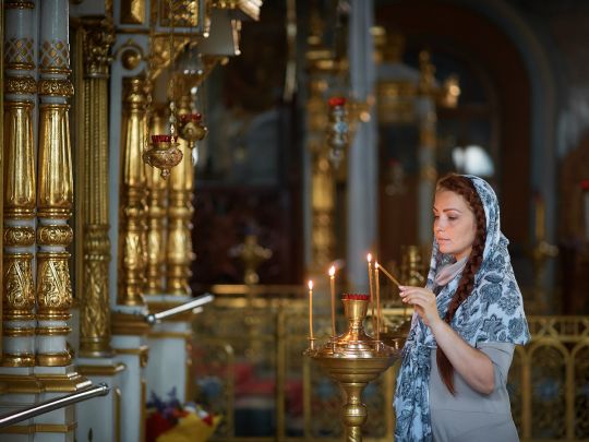 жінка ставить свічку в церкві