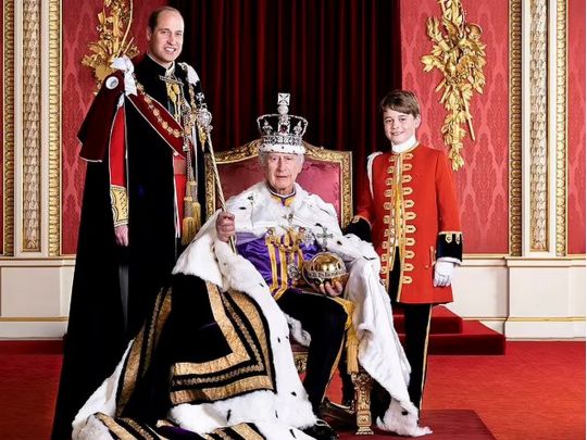 Чарльз ІІІ на троні в королівській мантії і короні. Поруч із ним спадкоємці престолу принц Вільям і принц Джордж