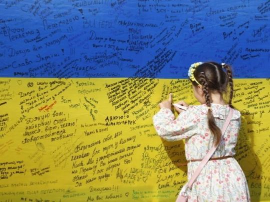 дівчинка пише на прапорі України