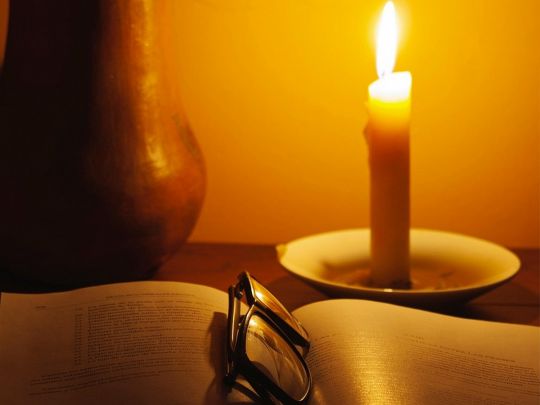 Свічка та книга на столі. Фото Pixabay